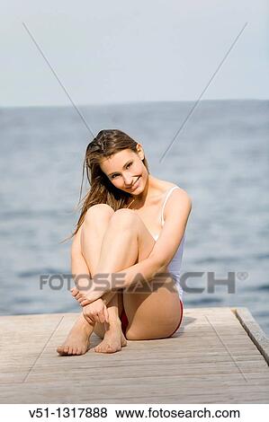 Portrait of a young woman smiling and sitting on a pier View Large Photo Image Stock Photo - Portrait of a young woman smiling and sitting on a pier. Fotosearch