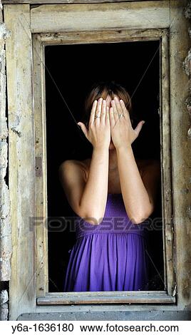 Portrait of a young woman standing in window frame covering face View Large Photo Image Stock Image - Portrait of a young woman standing in window frame covering face. Fotosearch