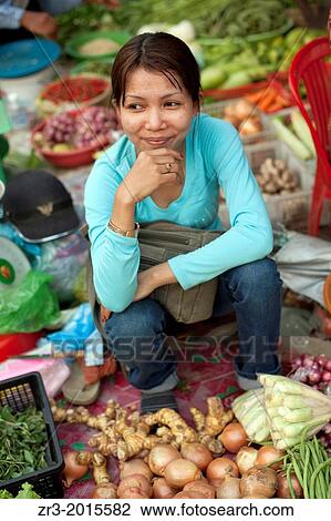 Stock Image - Portrait of a young woman vegetable vendor at a marketplace in Phnom Penh, Cambodia.. Fotosearch