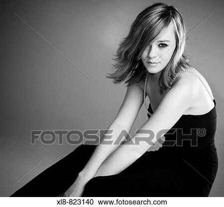 Stock Image - portrait of a young woman wearing a black evening dress, studio. Fotosearch