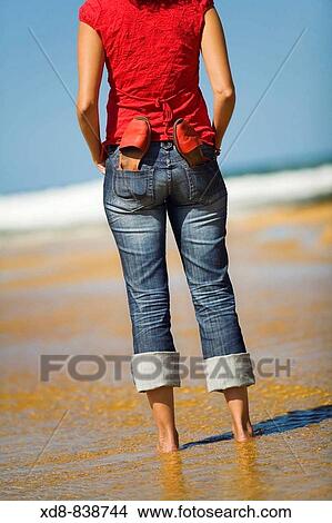 Picture - Portrait of a young woman with a pair of sandals on the beach. Fotosearch