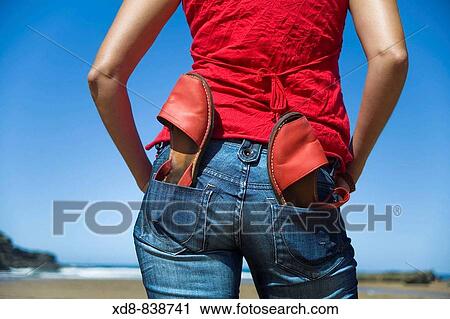 Stock Image - Portrait of a young woman with a pair of sandals on the beach. Fotosearch