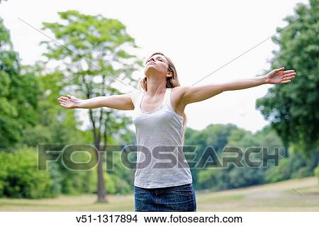 Portrait of a young woman with arms outstretched in the park View Large Photo Image Picture - Portrait of a young woman with arms outstretched in the park. Fotosearch