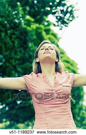 Portrait of a young woman with arms outstretched in the park View Large Photo Image Stock Photo - Portrait of a young woman with arms outstretched in the park. Fotosearch
