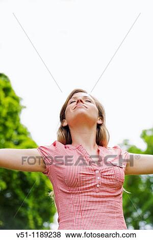 Portrait of a young woman with arms outstretched in the park View Large Photo Image Stock Photo - Portrait of a young woman with arms outstretched in the park. Fotosearch