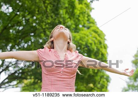 Portrait of a young woman with arms outstretched in the park View Large Photo Image Stock Photography - Portrait of a young woman with arms outstretched in the park. Fotosearch