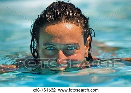 Stock Image - Portrait of a young woman with blue eyes in a swimming pool. Fotosearch