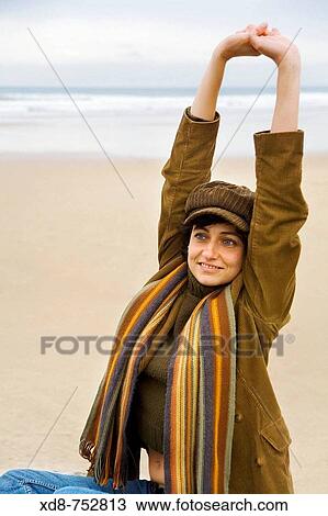 Portrait of a young woman with cap and scarf stretching out in a beach and smiling View Large Photo Image Stock Image - Portrait of a young woman with cap and scarf stretching out in a beach and smiling. Fotosearch