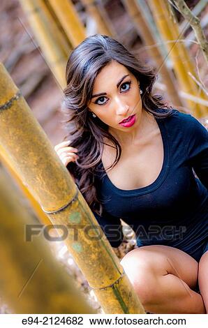 Portrait of a19 year old brunette woman looking directly at the camera wearing a black top surrounded by bamboo. View Large Photo Image Stock Image - Portrait of a19 year old brunette woman looking directly at the camera wearing a black top surrounded by bamboo.. Fotosearch
