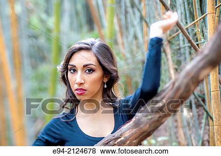 Portrait of a19 year old brunette woman looking directly at the camera wearing a black top surrounded by bamboo. View Large Photo Image Stock Photo - Portrait of a19 year old brunette woman looking directly at the camera wearing a black top surrounded by bamboo.. Fotosearch