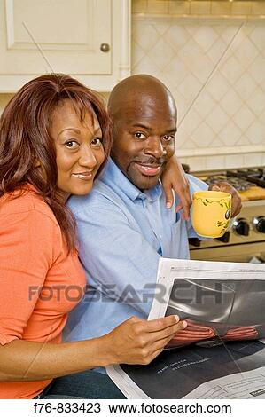 Portrait of African American couple in kitchen, reading morning paper together View Large Photo Image Stock Image - Portrait of African American couple in kitchen, reading morning paper together. Fotosearch