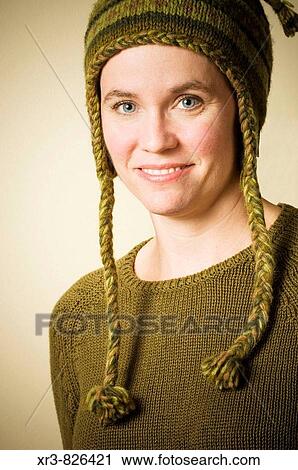 Stock Image - Portrait of an adult female in green sweater and knitted hat. Fotosearch
