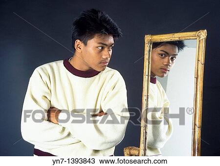 Portrait of an Asian teenage boy looking at himself in the mirror View Large Photo Image Stock Image - Portrait of an Asian teenage boy looking at himself in the mirror. Fotosearch