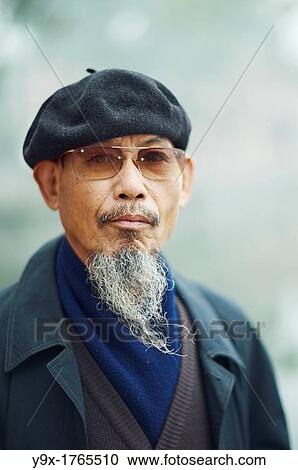 Stock Image - Portrait of an old man with a long beard wearing sunglasses and a beret. Fotosearch