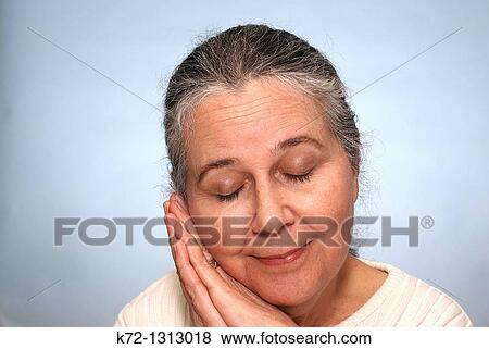 Stock Photo - Portrait of an older woman smiling and resting with eyes closed. Fotosearch