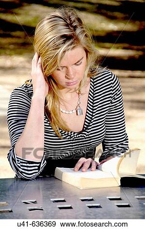 Portrait of attractive young female reading book on a windy day in tyhe park View Large Photo Image Stock Photo - Portrait of attractive young female reading book on a windy day in tyhe park. Fotosearch