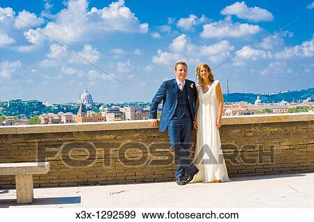 Stock Photo - Portrait of bride and groom standing on rooftop in Rome, Italy. Fotosearch