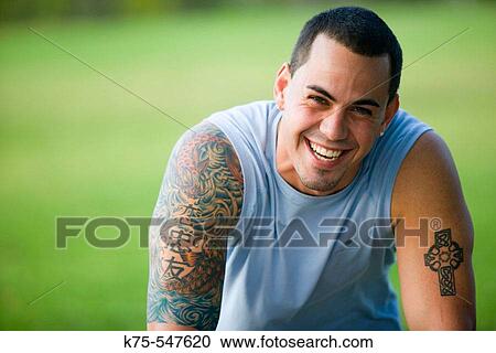 Stock Image - Portrait of Caucasian man in his 20's with tatoos smiling. Fotosearch