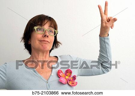 Portrait of Caucasian woman, fifties, brown hair and glasses, with positive expression and making the victory sign. View Large Photo Image Stock Photograph - Portrait of Caucasian woman, fifties, brown hair and glasses, with positive expression and making the victory sign.. Fotosearch