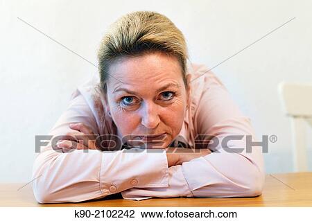 Stock Image - Portrait of caucasian woman laying on her folded arms on the table, Hamburg, Germany, Europe.. Fotosearch