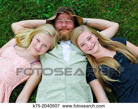 Portrait of dad with his two daughters on lawn View Large Photo Image Stock Photo - Portrait of dad with his two daughters on lawn. Fotosearch