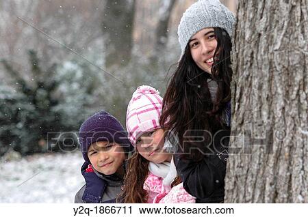 Portrait of family having fun behind a tree in the snow View Large Photo Image Stock Image - Portrait of family having fun behind a tree in the snow. Fotosearch