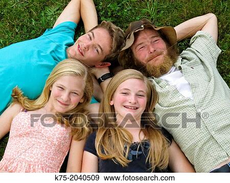 Stock Photo - Portrait of family lying down on lawn looking up. Fotosearch