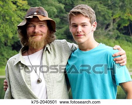 Stock Image - Portrait of father and teenage son outdoors. Fotosearch