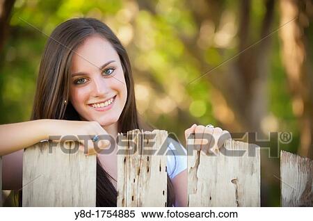 Stock Photography - Portrait of female caucasian teenager, 17 years old, behind old wooden fence in Concan, TEXAS, USA. Fotosearch