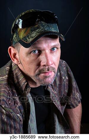 Stock Photo - Portrait of male adult, 40 years, Caucasian, in camouflage outfit with basecap. Fotosearch