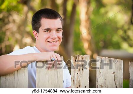 Portrait of male caucasian teenager, 17 years old, behind old wooden fence in Concan, TEXAS, USA View Large Photo Image Picture - Portrait of male caucasian teenager, 17 years old, behind old wooden fence in Concan, TEXAS, USA. Fotosearch