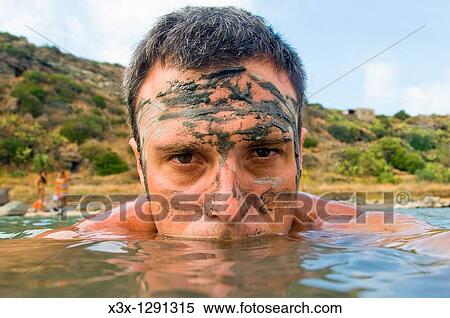 Stock Photography - Portrait of man covered in mud wading in lake, Lago Specchio di Venere, island of Pantelleria, Sicily, Italy. Fotosearch