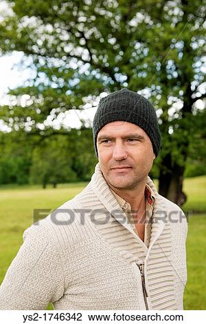 Portrait of man with a beanie standing in a park View Large Photo Image Stock Image - Portrait of man with a beanie standing in a park. Fotosearch