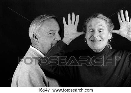 Stock Photo - Portrait of mature adults acting silly by sticking tongue out. Fotosearch