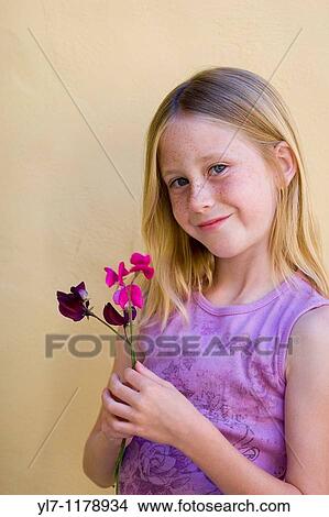 Portrait of nine-year old blonde blue eyed girl with freckles smiling while holding purple flowers View Large Photo Image Picture - Portrait of nine-year old blonde blue eyed girl with freckles smiling while holding purple flowers. Fotosearch