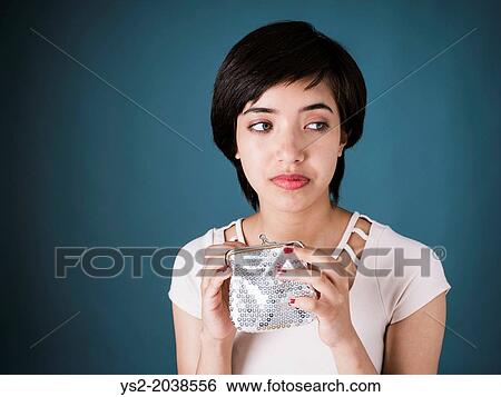 Stock Photograph - Portrait of sad young multiracial woman looking in empty silver wallet.. Fotosearch