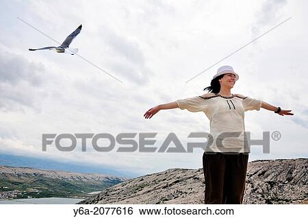Stock Photograph - Portrait of smiling mid adult woman with outstretched arms.. Fotosearch