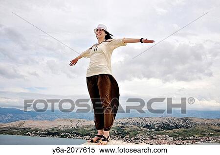 Portrait of smiling mid adult woman with outstretched arms standing on rock. View Large Photo Image Stock Photography - Portrait of smiling mid adult woman with outstretched arms standing on rock.. Fotosearch
