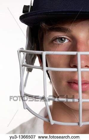Stock Photo - Portrait of teenage cricketer in protective helmet and visor. Fotosearch