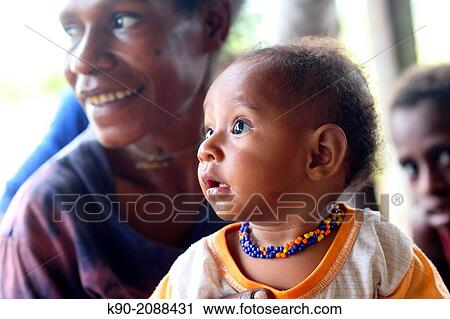 Stock Image - Portrait of toddler, hold by her mother, Papua, Indonesia, Southeast Asia.. Fotosearch