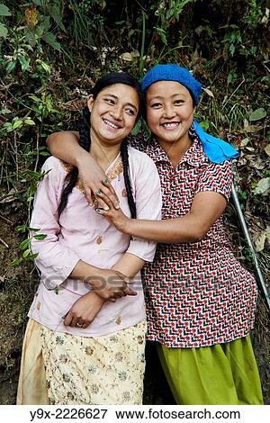 Stock Photo - Portrait of two young Tibetan female Labor workers embracing and laughing with each other.. Fotosearch