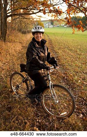 Stock Image - Portrait of woman alone outdoors on bicycle. Fotosearch