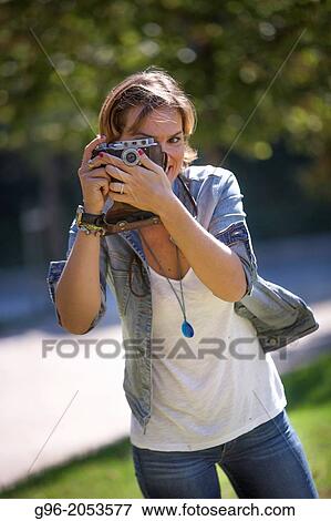 Stock Photo - Portrait of woman with old camera taking pictures.. Fotosearch
