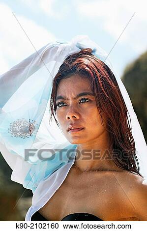 Stock Image - Portrait of young asian woman with white tissue in her hand and over her shoulders, Bali, Indonesia, Southeast Asia.. Fotosearch
