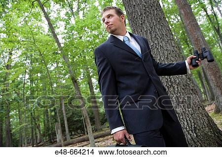 Portrait of young businessman in forest with binoculars View Large Photo Image Picture - Portrait of young businessman in forest with binoculars. Fotosearch