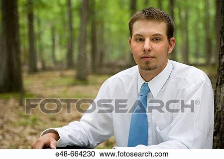 Portrait of young businessman sitting in forest View Large Photo Image Stock Image - Portrait of young businessman sitting in forest. Fotosearch