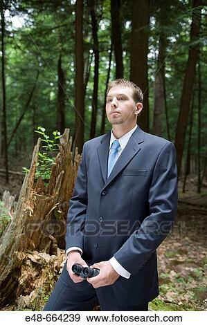 Stock Photo - Portrait of young businessman standing in forest. Fotosearch