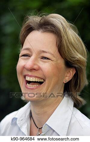 Picture - Portrait of young caucasian woman with sun glasses and short blond hair, laughing, holding her hands at the collar, Hamburg, Germany, Europe. Fotosearch