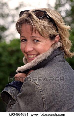 Portrait of young caucasian woman with sun glasses and short blond hair, smiling and looking into the camera, holding her hands at the collar, Hamburg, Germany, Europe View Large Photo Image Stock Image - Portrait of young caucasian woman with sun glasses and short blond hair, smiling and looking into the camera, holding her hands at the collar, Hamburg, Germany, Europe. Fotosearch