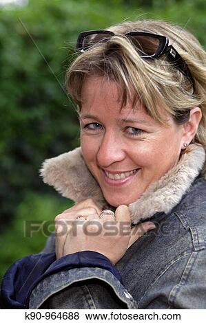 Portrait of young caucasian woman with sun glasses and short blond hair, smiling and looking into the camera, holding her hands at the collar, Hamburg, Germany, Europe View Large Photo Image Stock Photo - Portrait of young caucasian woman with sun glasses and short blond hair, smiling and looking into the camera, holding her hands at the collar, Hamburg, Germany, Europe. Fotosearch
